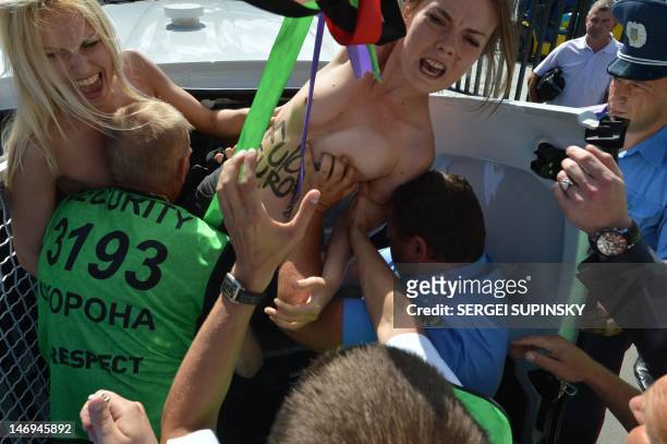 Policemen detain members of Ukraine's feminist group Femen including activist Oksana Shachko as they protest topless at the entrance of the Olympic...