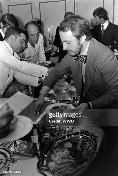 Pierre Berge serves himself from the buffet table at Charlotte Aillaud's party for Yves Saint Laurent.