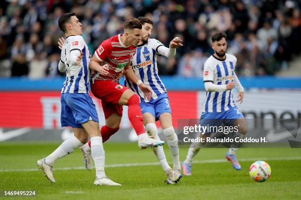 Ermedin Demirovic of FC Augsberg has a shot on goal whilst under pressure from Agustin Rogel of Hertha Berlin during the Bundesliga match between...