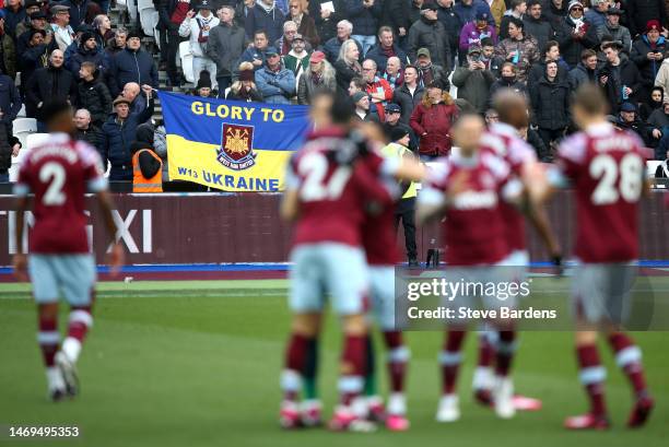 West Ham United fans hold a flag which reads 'Glory To Ukraine' to indicate peace and sympathy with Ukraine one year on prior to the Premier League...