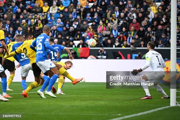 Julian Brandt of Borussia Dortmund scores the team's first goal whilst under pressure from as Oliver Baumann of TSG Hoffenheim looks on during the...