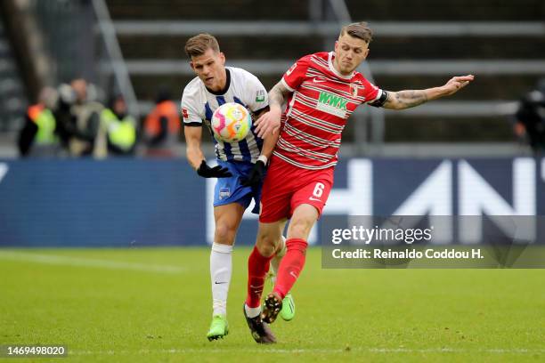 Florian Niederlechner of Hertha BSC battles for possession with Jeffrey Gouweleeuw of FC Augsburg during the Bundesliga match between Hertha BSC and...