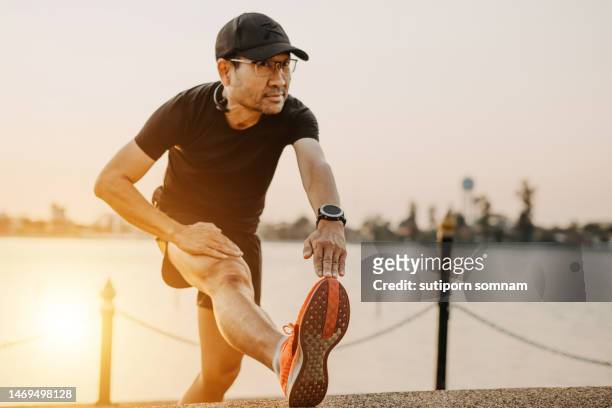 middle-aged man warming up before running - warming up for exercise stock pictures, royalty-free photos & images