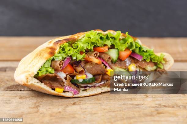 doener kebab doner kebap fast food meal in pita bread on wooden board in stuttgart, germany - doner kebab stock pictures, royalty-free photos & images