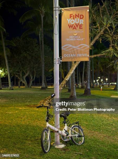 city bicycle chained up on miami beach sign post advertising the lifestyle along ocean drive - motto stockfoto's en -beelden