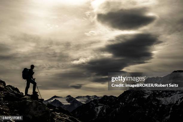 climbers on rocks in backlight with cloudy sky in the background south tyrolean mountains, martell valley, merano, vinschgau, south tyrol, italy - martell valley italy - fotografias e filmes do acervo