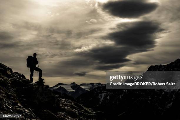 climbers on rocks in backlight with cloudy sky in the background south tyrolean mountains, martell valley, merano, vinschgau, south tyrol, italy - martell valley italy - fotografias e filmes do acervo