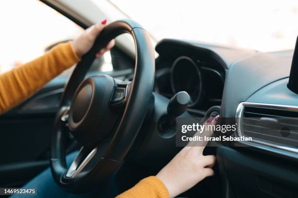 side view of the arms of an unrecognizable woman pressing the ignition button of her car. - hand steering wheel stock pictures, royalty-free photos & images