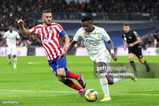 Vinicius Junior of Real Madrid runs with the ball whilst under pressure from Koke of Atletico Madrid during the LaLiga Santander match between Real...