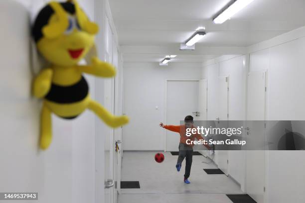 Refugee child from war-torn eastern Ukraine kicks a ball in the container shelter that is his new, temporary home on February 25, 2023 in Lviv,...