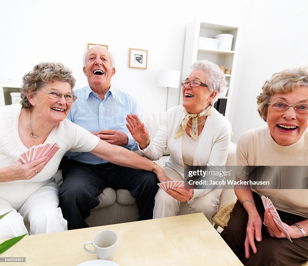 Happy senior man and women playing cards at home