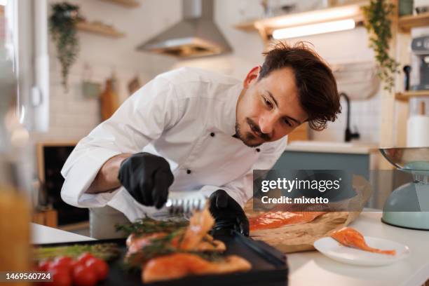 young professional chef grilling salmon on a electric grill at his home based food store - home chef stock pictures, royalty-free photos & images