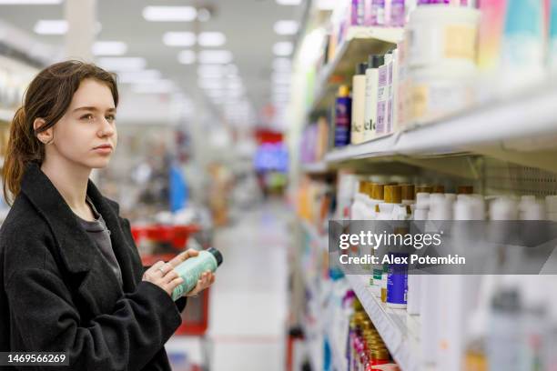 jeune femme choisissant le shampooing dans le magasin. - femme shampoing photos et images de collection