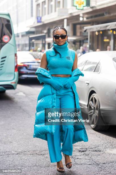 Temiloluwa Otedola wears turquoise cropped turtleneck knit, pants, puffer coat, heeled sandals, sunglasses outside Ermanno Scervino during the Milan...
