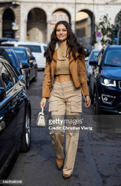 Marica Pellegrinelli wears beige cropped knit, shearling jacket, pants with side pockets, bag outside Ermanno Scervino during the Milan Fashion Week...