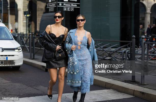 Marta Lozano wears black leather skirt top, jacket, bag & Teresa Andres Gonzalvo wears blue laced dress, coat with print outside Ermanno Scervino...