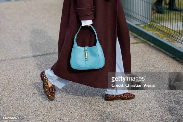 Guest wears blue Gucci bag, rust brown coat outside Ferragamo during the Milan Fashion Week Womenswear Fall/Winter 2023/2024 on February 25, 2023 in...