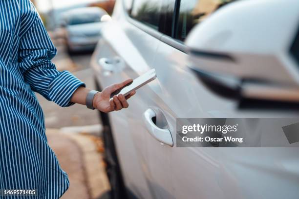 close-up of young woman using digital key on smartphone to unlock, lock and start a car - car rental stockfoto's en -beelden