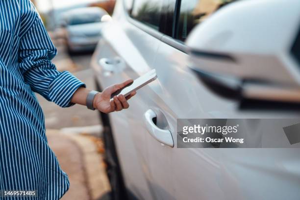 close-up of young woman using digital key on smartphone to unlock, lock and start a car - car rental stock pictures, royalty-free photos & images