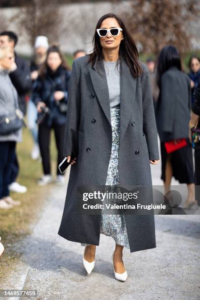 Guest is seen wearing white sunglasses, a grey long coat, a light grey sweaters, white pumps and a sequin silver midi skirt outside the Ferragamo...