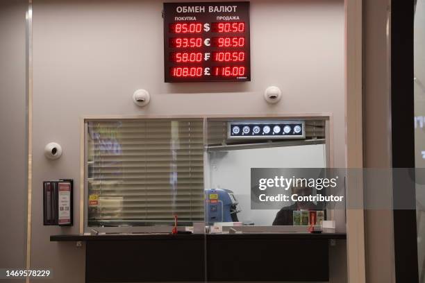 Cashier seen in the window under an electronic panel with exchange rates of the ruble to the U.S. Dollar and Euro, at the exchange office of the Fora...
