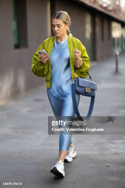 Guest is seen wearing Dior earrings, bracelet and ring, a pearl and gold necklace, white sneakers, an ocean blue satin maxi long dress, an acid green...