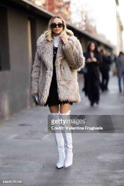 Candela Pelizza is seen wearing Fendi black sunglasses, a fur beige coat, a white turtleneck shirt, a black mini dress with star details and white...