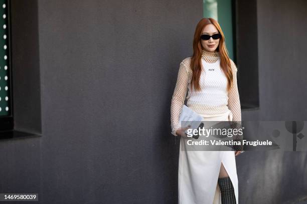 Guest is seen wearing black sunglasses, a white fishnet long-sleeved turtleneck shirt with a MSGM white tank top under, a cream wrap skirt, long...