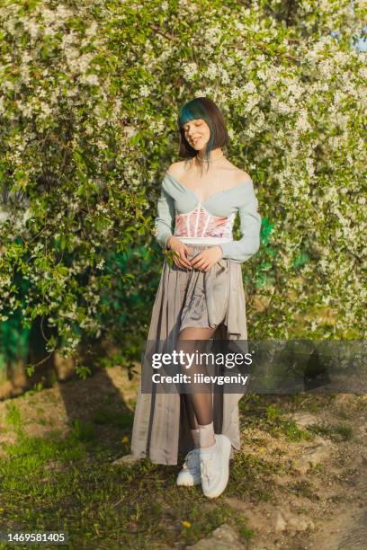 mulher asiática com cabelo azul no fundo de uma árvore florida. penteado bang. jardim de primavera. flores brancas - corset - fotografias e filmes do acervo