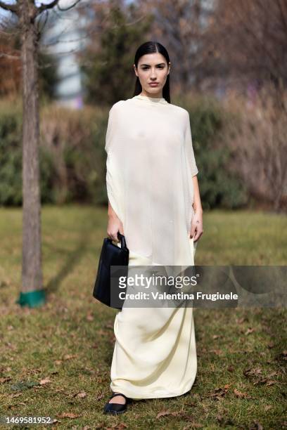 Patricia Manfield, aka Heir, is seen wearing a long see through pale yellow dress and black bag and Mary Janes sandals outside the Ferragamo show...