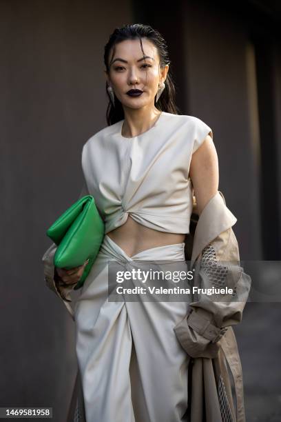 Jessica Wang is seen wearing silver triangle earrings, a light-beige long maxi trench with white fabric details, a green leather handbag, a white...