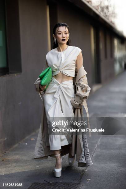 Jessica Wang is seen wearing silver triangle earrings, a light-beige long maxi trench with white fabric details, a green leather handbag,a white...