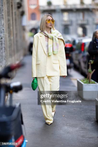 Guest is seen wearing a light yellow pant suit, yellow lens sunglasses and sweater over the shoulders outside the Dolce & Gabbana show during the...