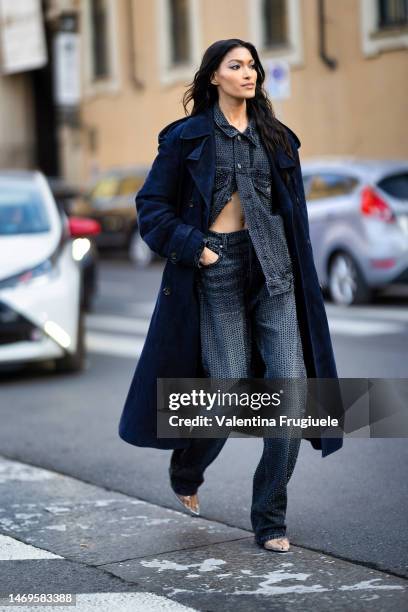 Guest is seen wearing a blue suede long trench, transparent plastic pumps, an animalier printed handbag and a denim coord-set made of a jacket and...