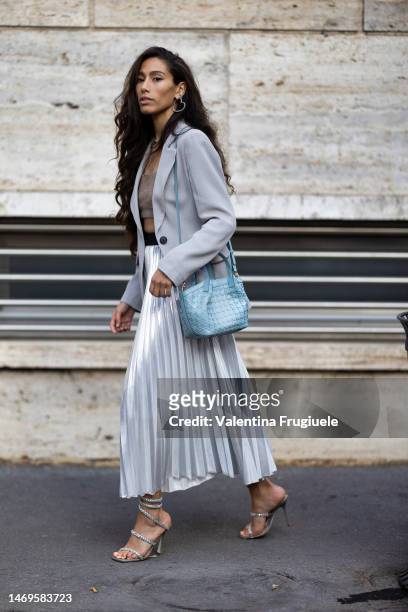 Guest is seen wearing heart-shaped silver and diamonds earrings, a light grey blazer, a beige cashmere bra top, a pearl necklace, a long maxi...