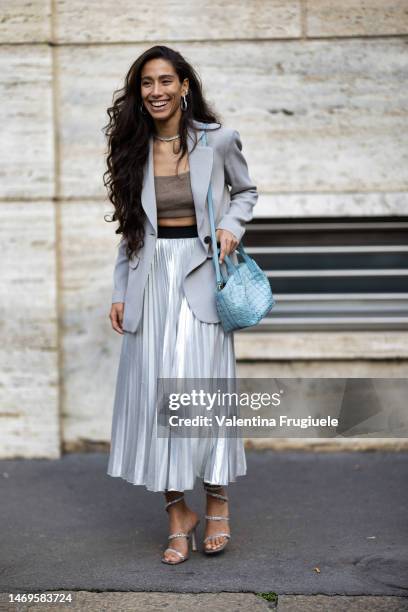 Guest is seen wearing heart-shaped silver and diamonds earrings, a light grey blazer, a beige cashmere bra top, a pearl necklace, a long maxi...