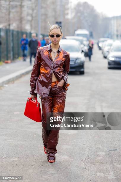 Vanessa Hong wears burgundy orange suit, red bag outside Ferragamo during the Milan Fashion Week Womenswear Fall/Winter 2023/2024 on February 25,...