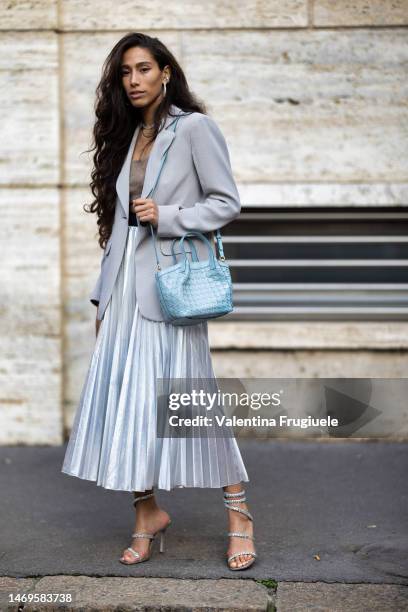 Guest is seen wearing heart-shaped silver and diamonds earrings, a light grey blazer, a beige cashmere bra top, a pearl necklace, a long maxi...