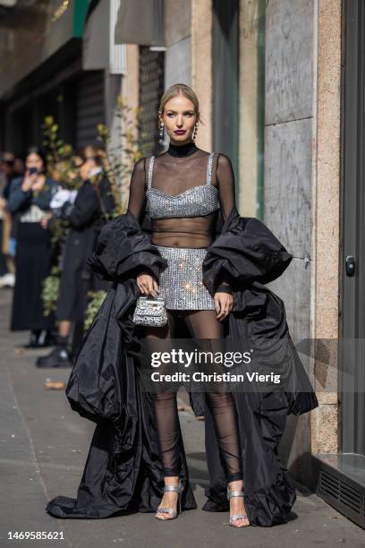 Leonie Hanne wears top and skirt with rhinestones, bag, black transparent dress, coat outside Dolce & Gabbana during the Milan Fashion Week...