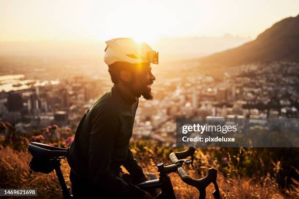 mountain bike, sports and black man for fitness, travel or triathlon training in morning sunrise and cityscape. adventure, nature and success of cycling person on bike and safety gear on rock journey - triathlon gear stock pictures, royalty-free photos & images