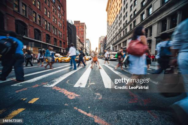 crowd of people crossing the street in midtown manhattan - oversteekplaats stockfoto's en -beelden