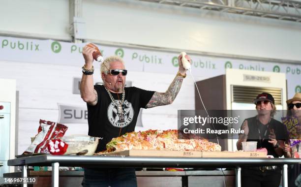 Guy Fieri adds sauce to a giant burrito during the 2023 South Beach Wine and Food Festival on February 25, 2023 in Miami Beach, Florida.