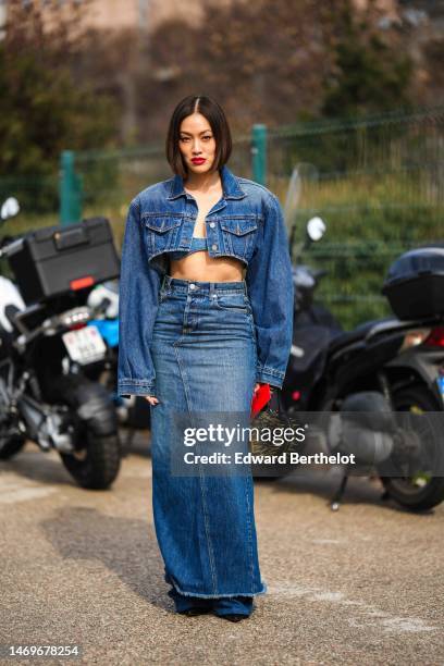 Tiffany Hsu wears a blue denim cropped oversized jacket, a blue denim V-neck / cropped top, a high waist blue denim long tube skirt, a black shiny...