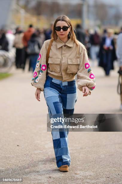 Julia Comil wears black sunglasses, a beige denim with embroidered braided wool long sleeves with embroidered pink / green flower pattern jacket,...