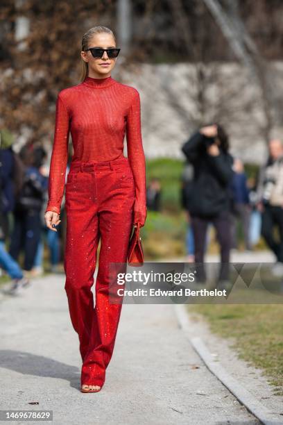 Caroline Daur wears black sunglasses, a red glitter / embroidered rhinestones high neck / long sleeves t-shirt, red red with embroidered rhinestones...