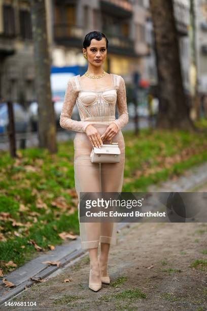 Anna Rosa Vitiello wears gold earrings, a gold DG logo pattern large necklace from Dolce & Gabbana, a beige lace flower pattern long sleeves / square...