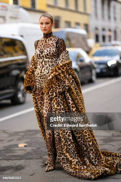 Guest wears a beige with brown leopard print pattern turtleneck / long sleeveless long dress, a beige / black / brown leopard print pattern fur long...