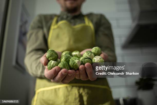 mans hands holding handful of brussels sprouts. - handvol stockfoto's en -beelden