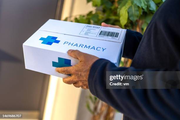 mani dell'addetto alle consegne che tengono il pacco dei farmaci - consegna a domicilio foto e immagini stock