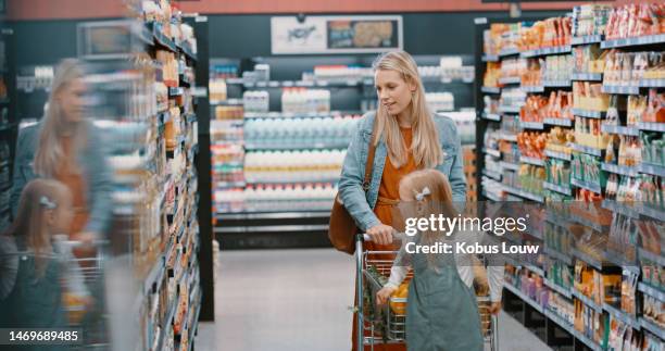 grocery, shopping and mother with kid at the store, shop or supermarket buying food and using a trolley or cart. mommy, single parent and customer mom with daughter or child purchase groceries aisle - woman supermarket stockfoto's en -beelden